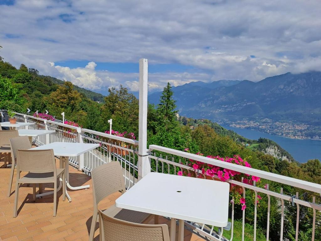 balcón con mesas y sillas y vistas a las montañas en B&B VISTA LAGO, en Bellagio