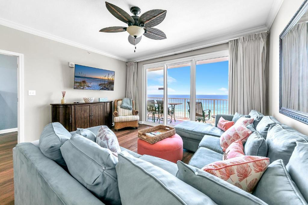 a living room with a blue couch and a large window at Grandview East 702 in Panama City Beach