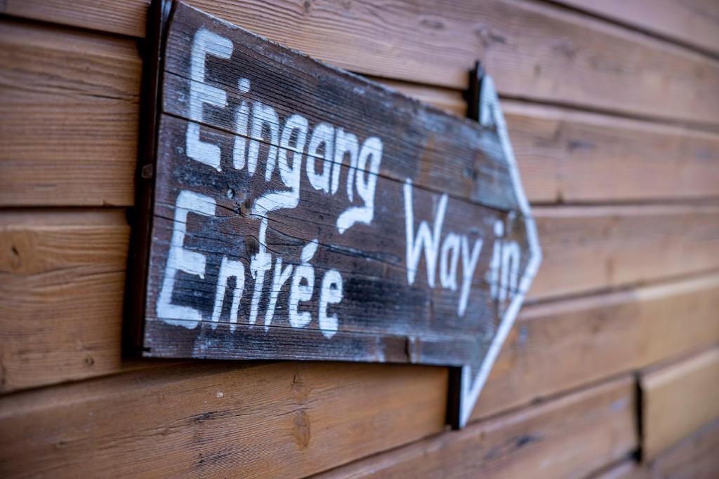 a sign on the side of a wooden wall at Simons Herberge in Meiringen