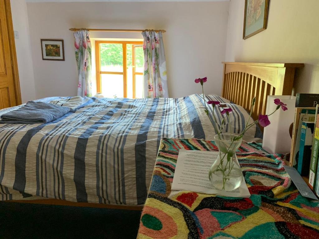 Un dormitorio con una cama y un jarrón con flores. en Lara's House, en Balderstone