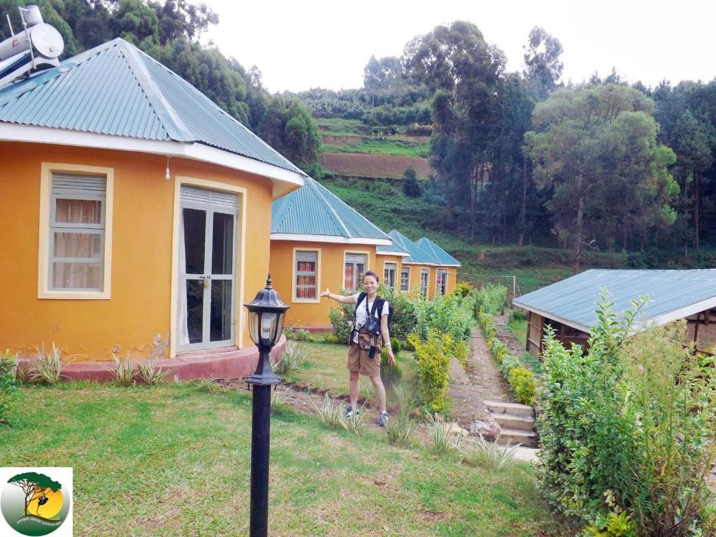 a man standing in front of a yellow house at Antique cottages in Kabale