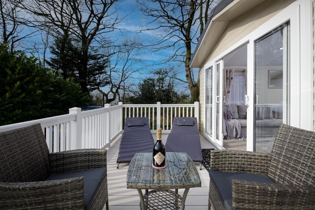 a patio with chairs and a table on a porch at Ribble Heights - Cosy Tree-Top Glamping Lodge with Balcony in Longridge