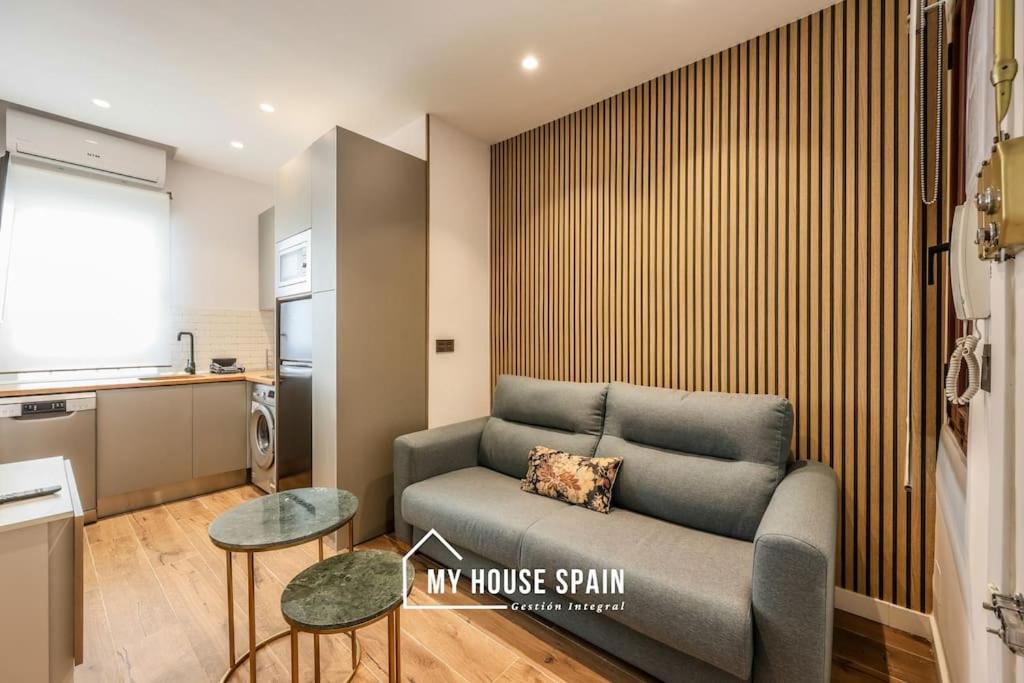 uma sala de estar com um sofá e uma cozinha em MyHouseSpain - Moderno apartamento en el centro em Madri