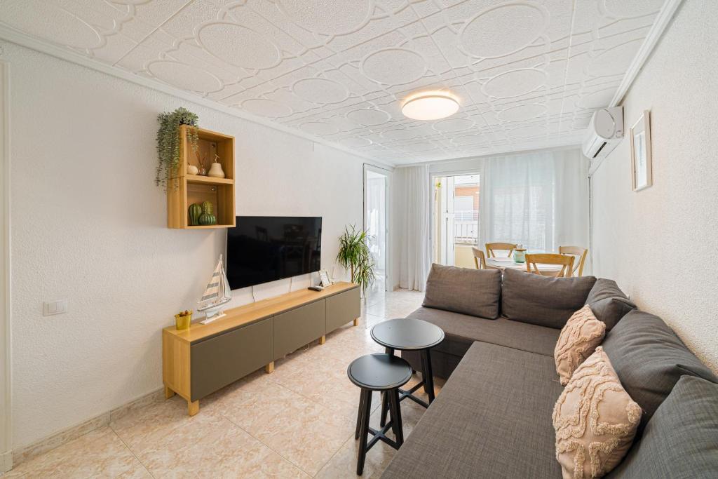 Una sala de estar con un sofá y un televisor. en Casita del Puerto 3, en Santa Pola