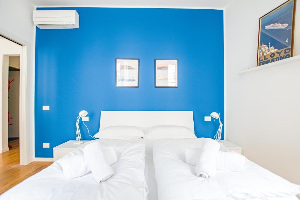 een slaapkamer met een blauwe muur en een wit bed bij G10 in Trieste