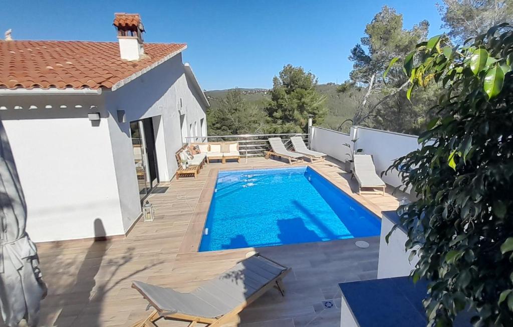 a swimming pool on a deck with a house at Villa Avril piscina privada y amplias terrazas in Olivella