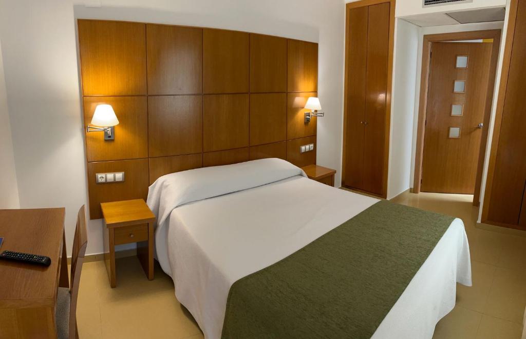 a bedroom with a large white bed and wooden walls at Hotel Tio Pepe in Peniscola