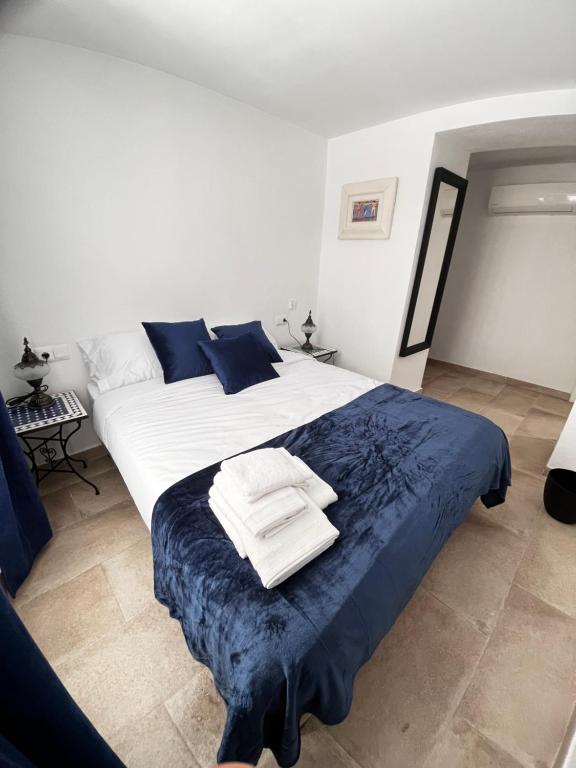 1 dormitorio con 1 cama blanca grande con sábanas azules en Shanti’s Andalusian Rooms, en Málaga