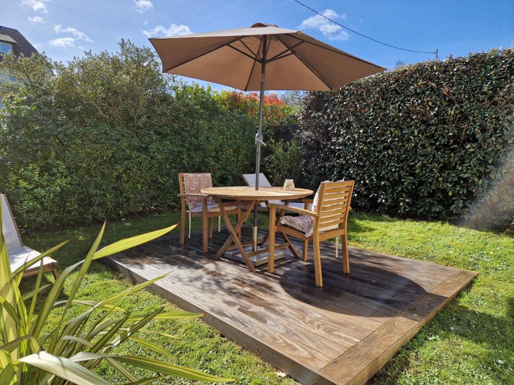 einen Holztisch und Stühle mit Sonnenschirm in der Unterkunft Le Bois in Honfleur