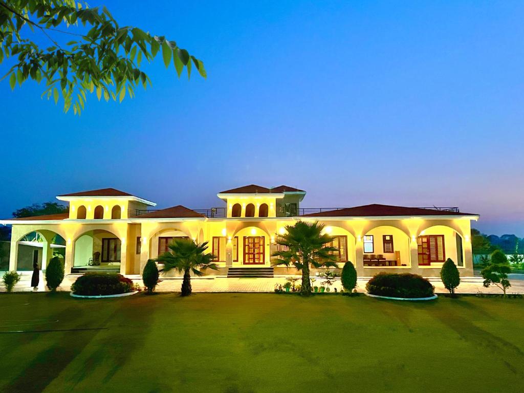 a large white house with palm trees in front of it at Bundeli Kothi - a unique farmstay in Orchha