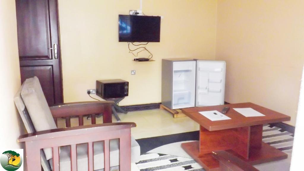 een kleine kamer met een tafel en een tv aan de muur bij Antique Apartments in Entebbe