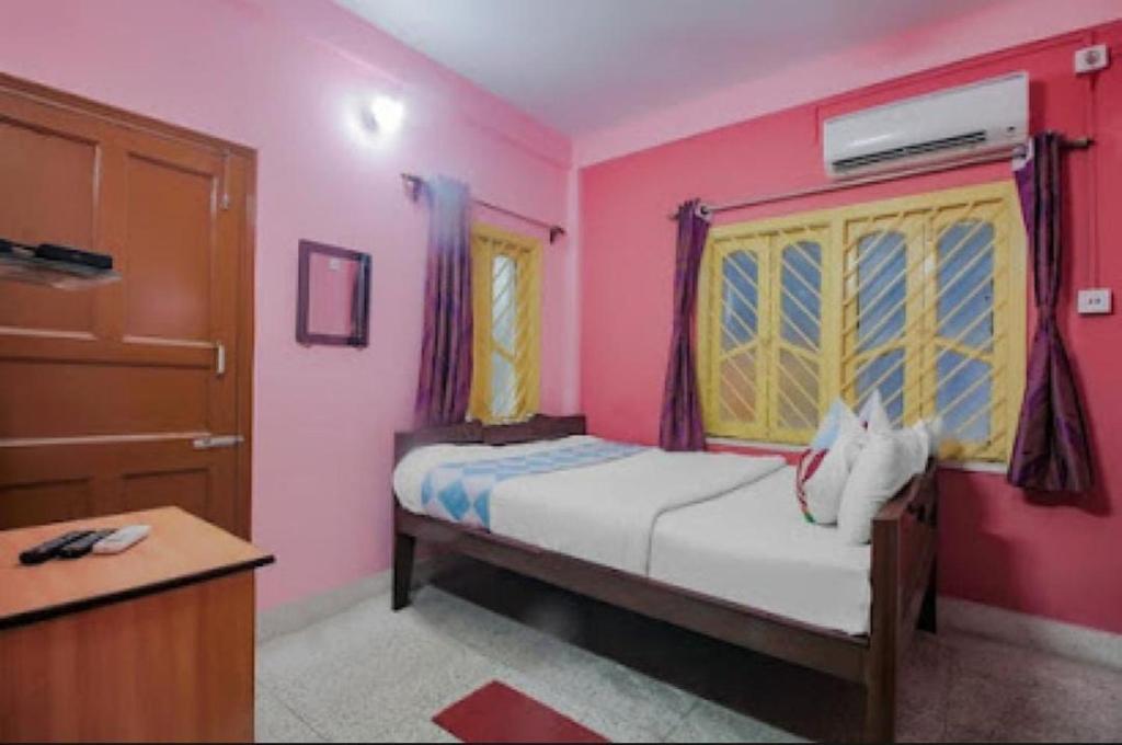 a pink bedroom with a bed and a dresser at The Orchid Inn in Kolkata