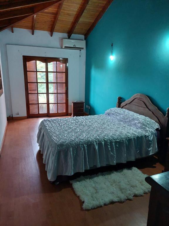 - une chambre avec un lit et un mur bleu dans l'établissement Chalet de ladrillos y tejas, à La Plata