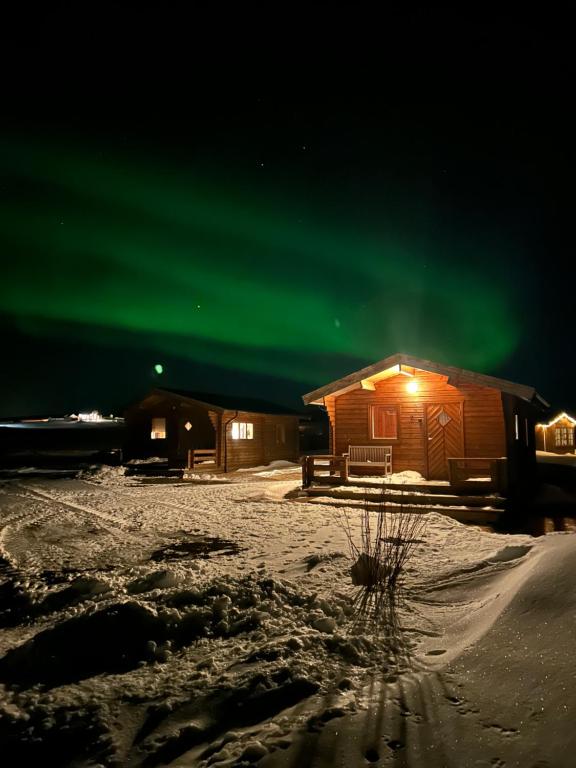 una cabina con l'aurora boreale verde nel cielo di Guesthouse Didi a Flagbjarnarholt