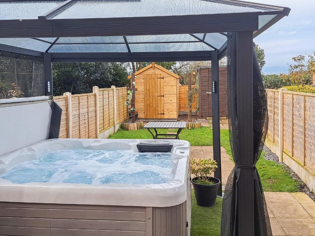 a hot tub in a backyard with an umbrella at Cernunnos Cottage in Leven