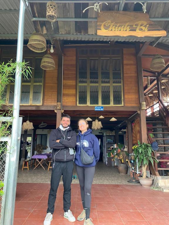Ein Mann und eine Frau stehen vor einem Gebäude in der Unterkunft Homestay Chinh Bi in Yên Bái