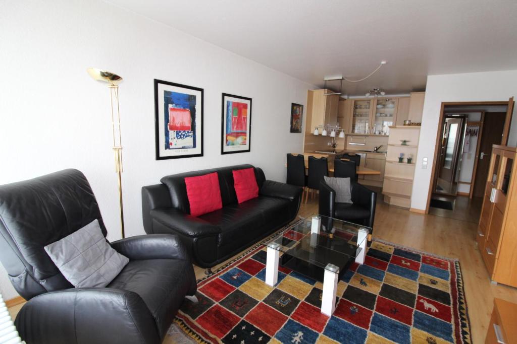 ein Wohnzimmer mit schwarzen Ledermöbeln und einem Tisch in der Unterkunft Haus Norderhoog Wohnung 56 in Westerland