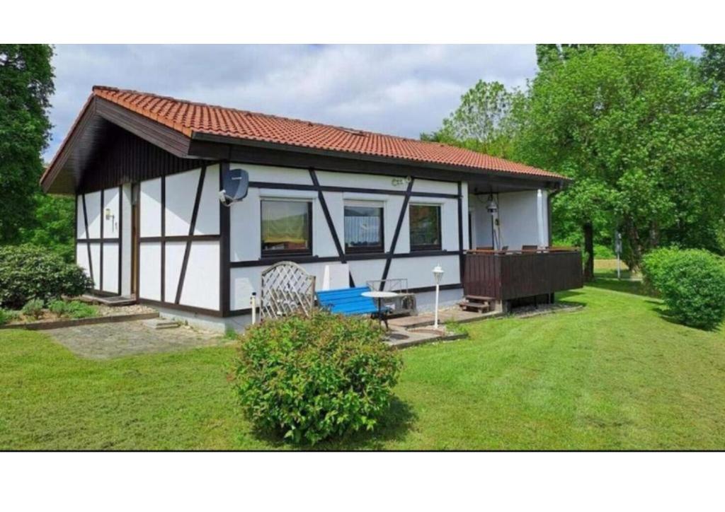 a small white house with a red roof at 1 - Gemütlicher Bungalow am Fuße der Wasserkuppe in Dipperz