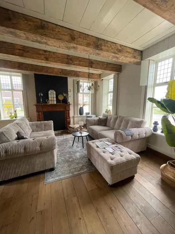 a living room with two couches and a table at Zeer sfeervol gastenverblijf in Het Molenhuisje met woonkamer en keuken in Winschoten