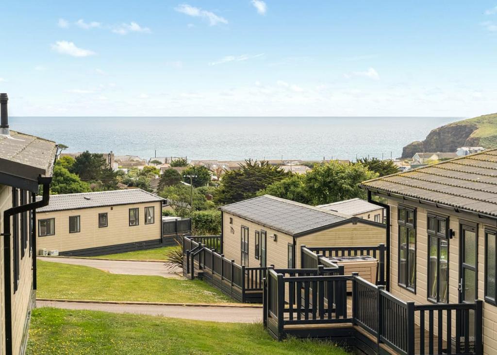 a row of houses with the ocean in the background at Praa Sands Holiday Park in Saint Hilary
