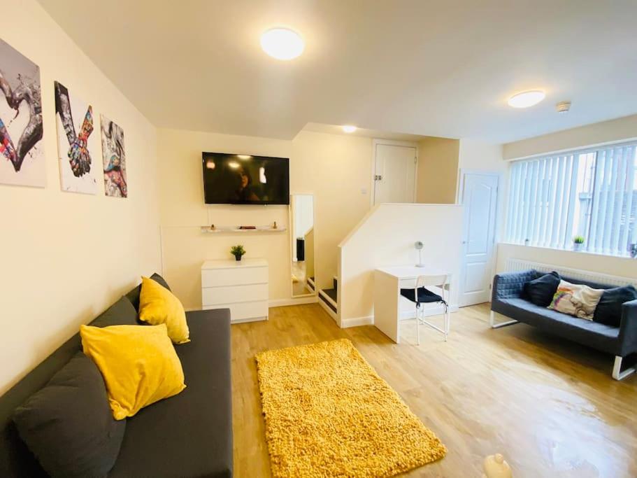 un soggiorno con divano nero e cuscini gialli di Luton Luxury Apartment a Luton