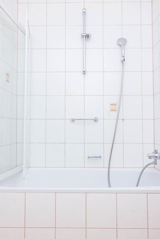 a shower in a white tiled bathroom at Haus Kella-Egg in Brand