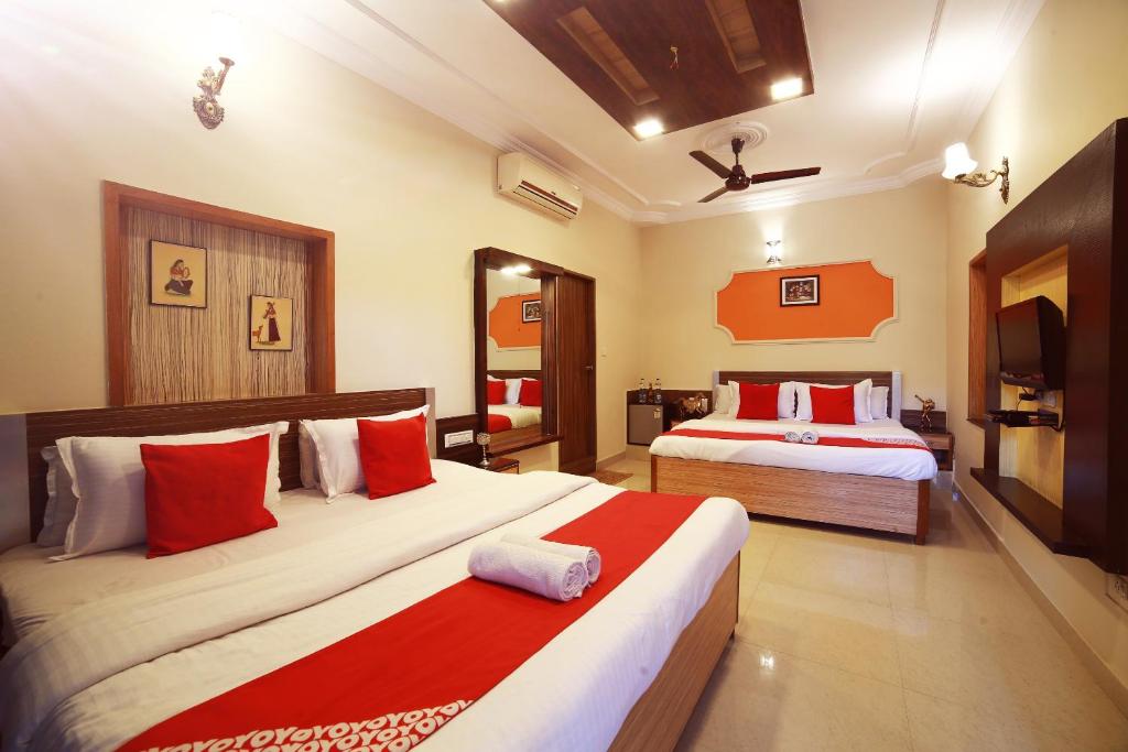 a bedroom with two beds with red and white pillows at EMINENCE - PALM RESIDENCY (1.5 KM FROM NAKKI LAKE) in Mount Ābu