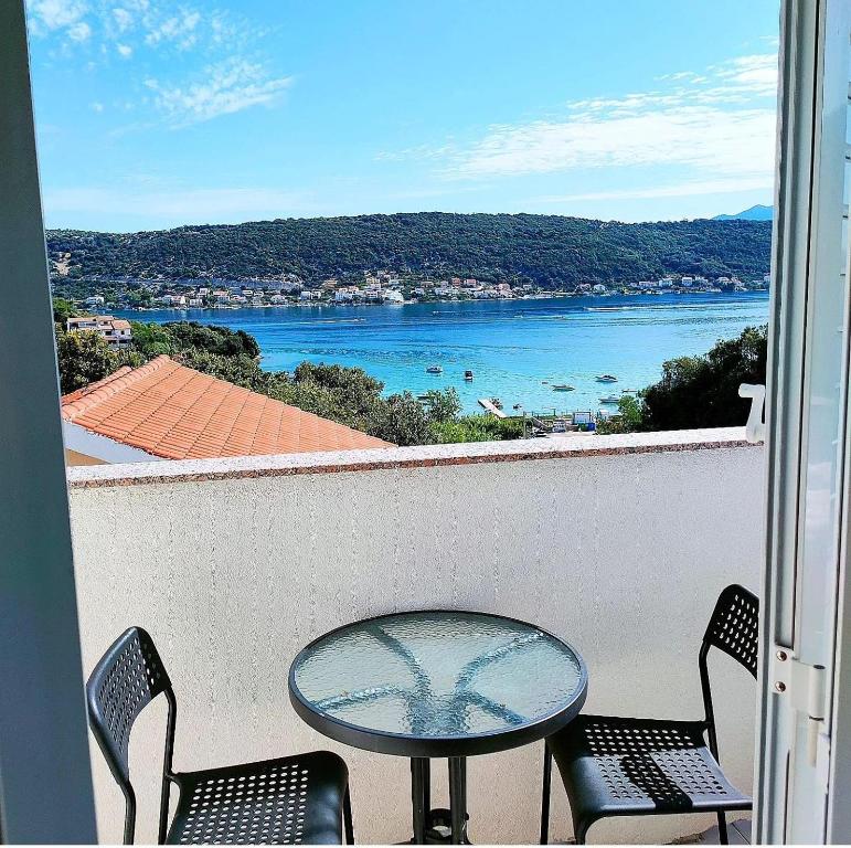 a table and chairs on a balcony with a view of the water at Rab Island Apartments Del Sole in Supetarska Draga