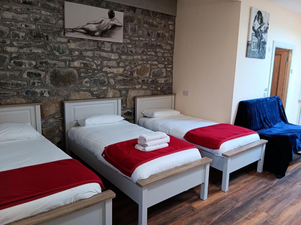 3 camas en una habitación con una pared de piedra en Matty's Pub - Apartment's en Carlow