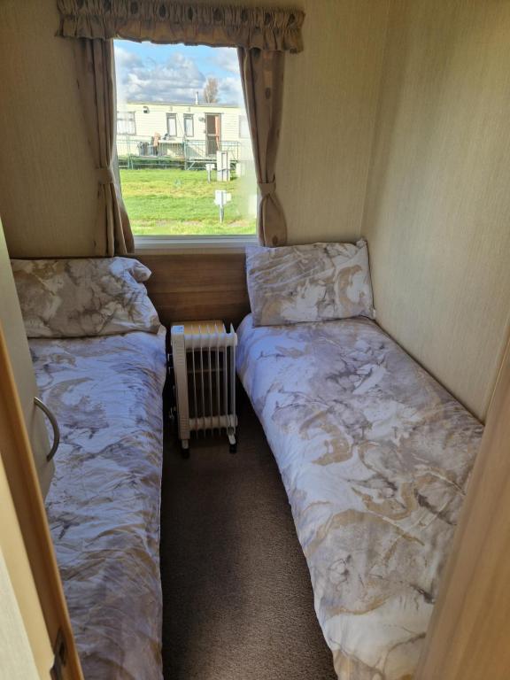 two beds in a small room with a window at Woods caravan in Ingoldmells