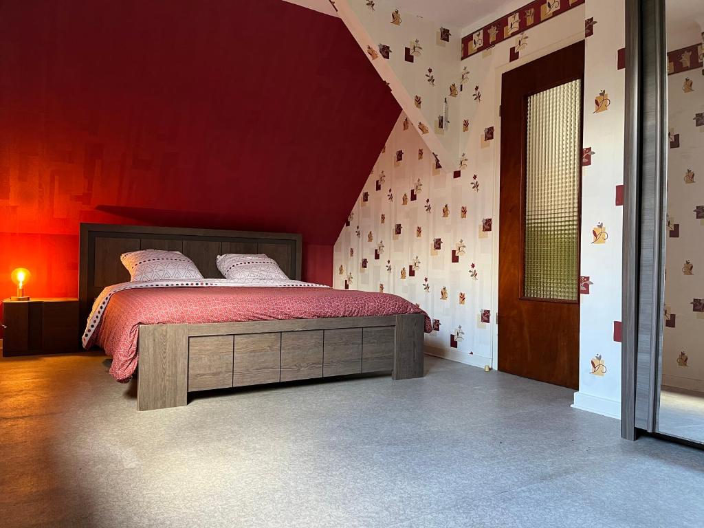 um quarto com uma cama com uma parede vermelha em La Terasse des Vignes - Maison 2 Chambres - 4 Personnes em Blienschwiller