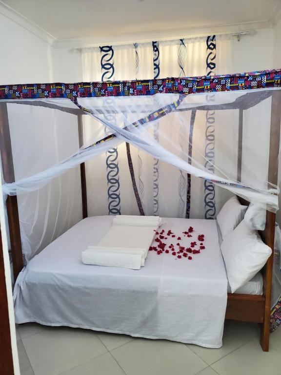 a bed with a canopy with red roses on it at Nungwi 14 bnb in Nungwi
