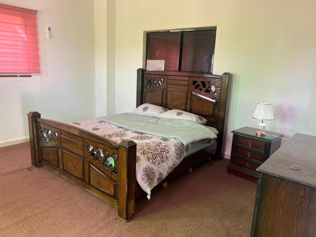 a bedroom with a wooden bed and a mirror at Red rose apartment in Jerash