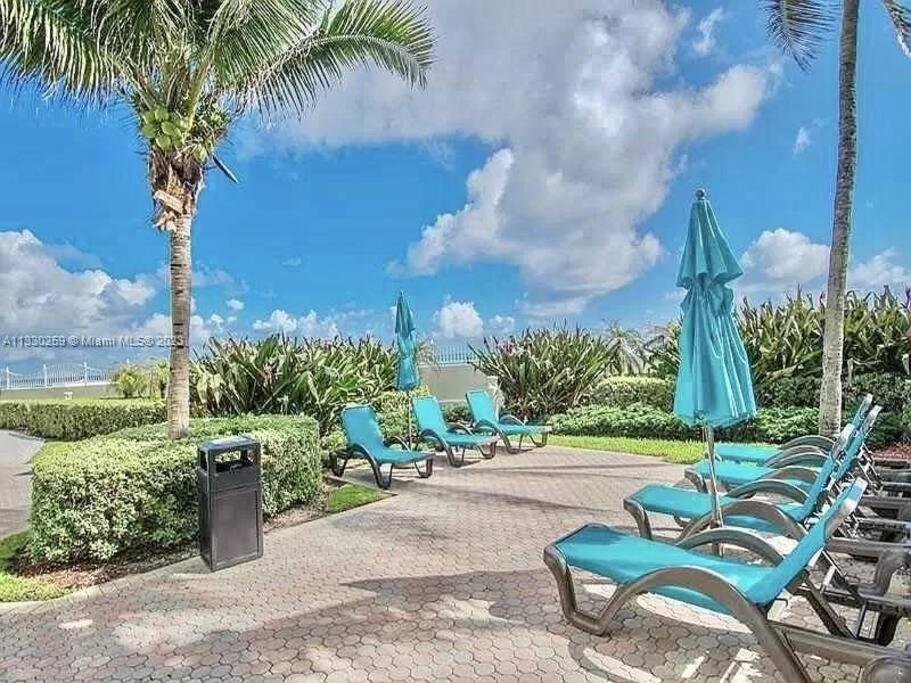 een rij blauwe ligstoelen en parasols bij Oceanview 2 bdrm Beachfront Condo Hollywood FL in Hollywood