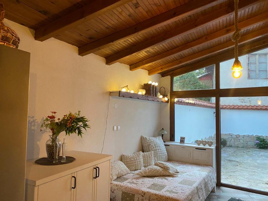 ein Wohnzimmer mit einem Sofa und einem großen Fenster in der Unterkunft Къща за гости Casa Per Te in Marchevo