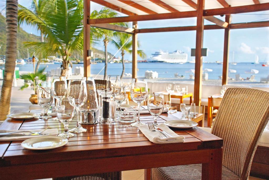 a wooden table with wine glasses on it with a view of the ocean at Holland House Beach Hotel in Philipsburg