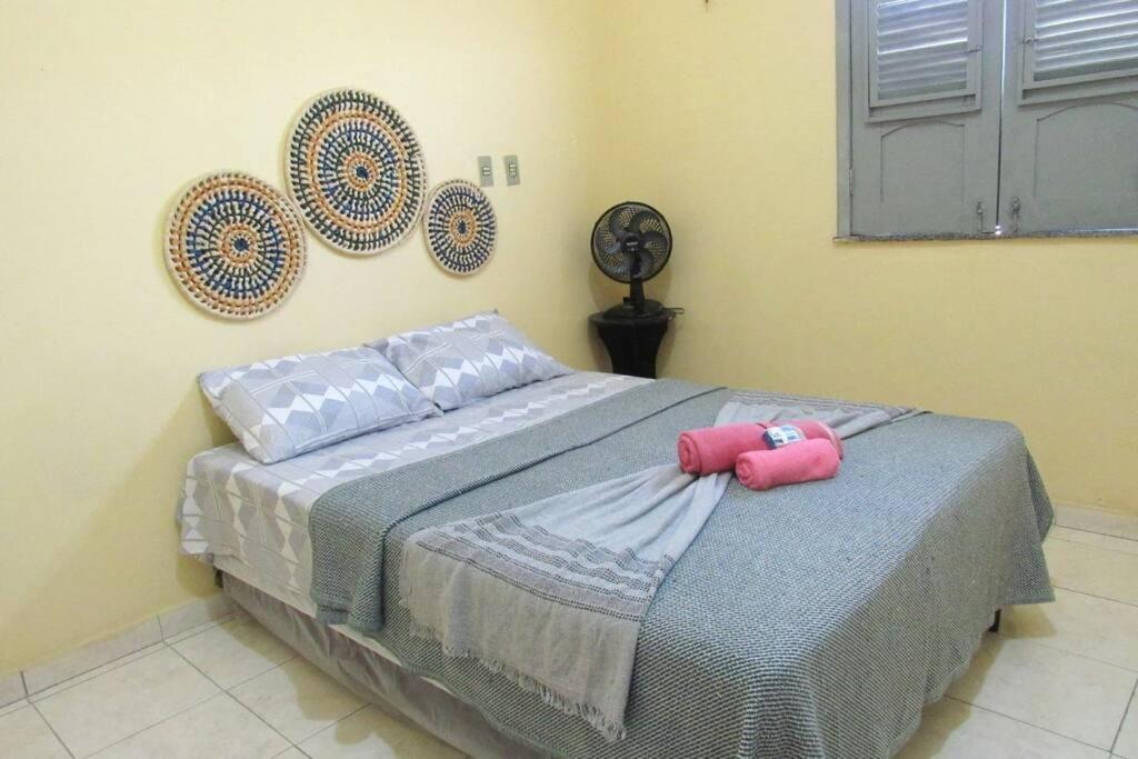 1 dormitorio con 1 cama con 2 almohadas rosas en Casa praiana - agradável e confortável ambiente com ar-condicionado, en Parnaíba