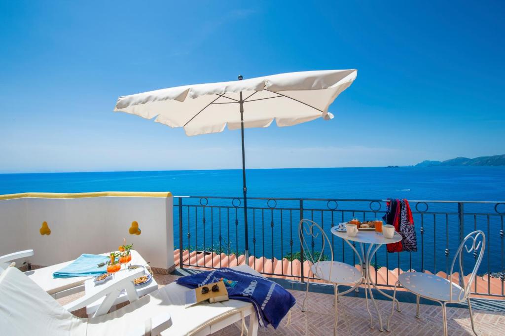 eine Terrasse mit einem Sonnenschirm, einem Tisch und Stühlen in der Unterkunft CASA OLGA, UN AFFACCIO SUL MARE !! in Praiano