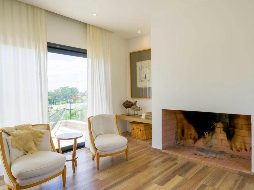 a living room with a fireplace and two chairs at Casa EL ORIGEN in Tandil