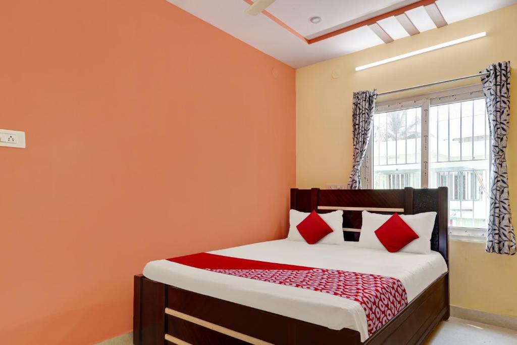 a bedroom with orange walls and a bed with red pillows at Super OYO SEA COASTAL INN-3 in Kākināda