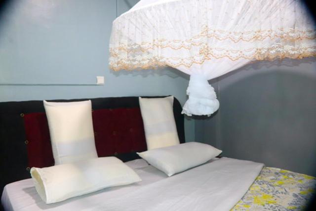 a bed with white sheets and pillows and a lamp at Zeyman’s Appartments in Kigali