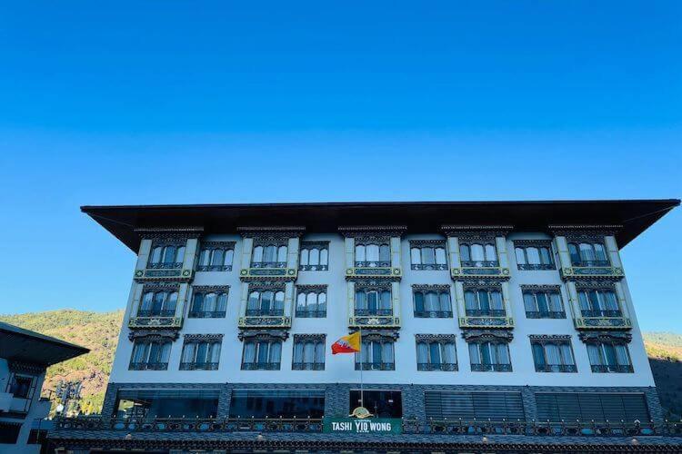 un grande edificio bianco con una bandiera di Tashi Yid Wong Grand a Thimphu