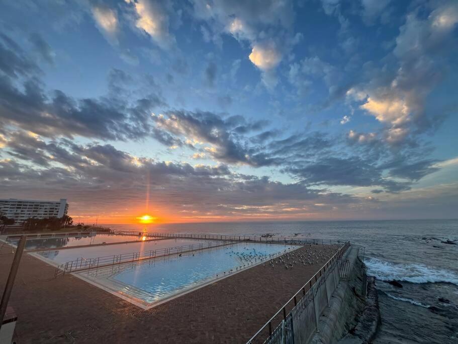 a sunset over a swimming pool on the beach at Sea Point at Princeton Place in Cape Town