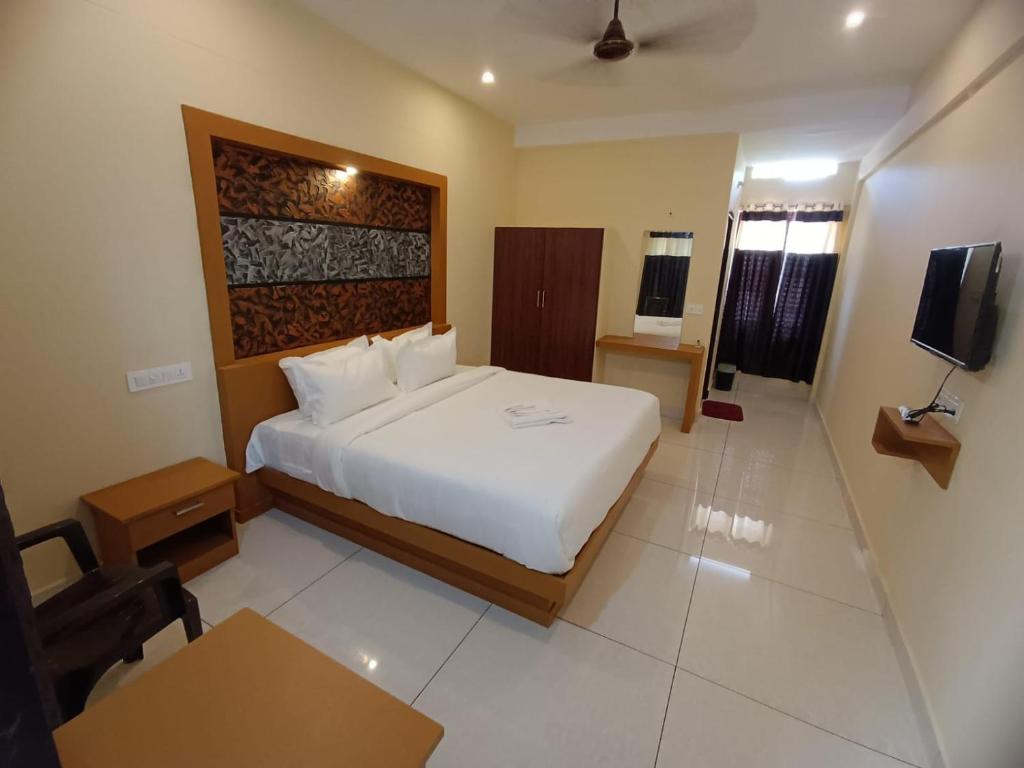 a hotel room with a bed and a television at MADAVATH RESIDENCY in Kenichira