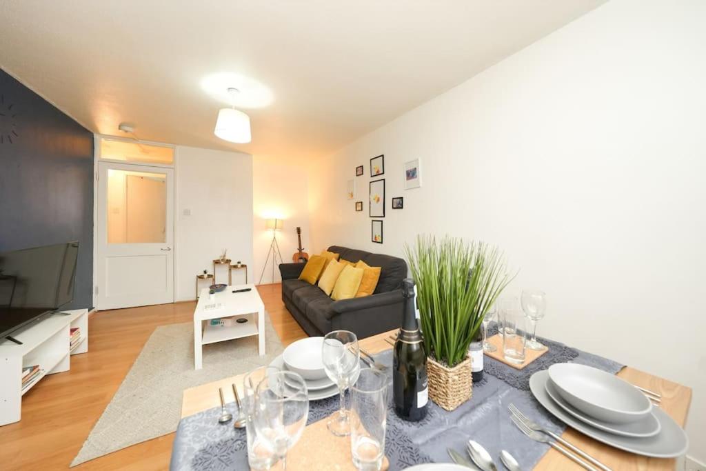 a living room with a couch and a table with plates at Cosy One Bedroom Apartment in London