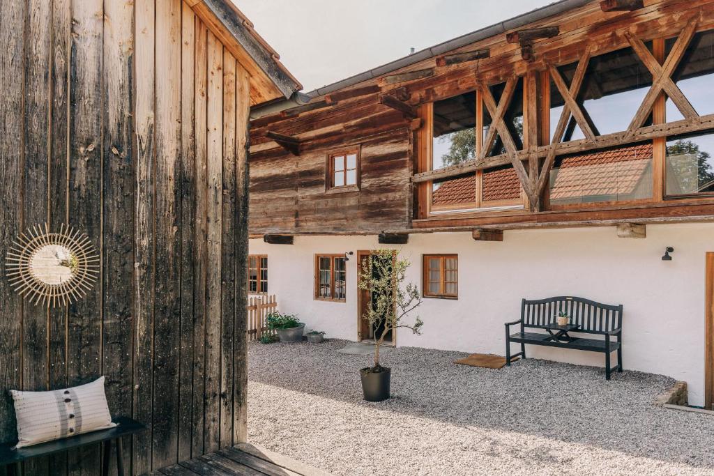 a wooden building with a bench in the courtyard at Bauernchalet elbacher gütel - Exklusives Ferienhaus am Starnberger See in Eurasburg