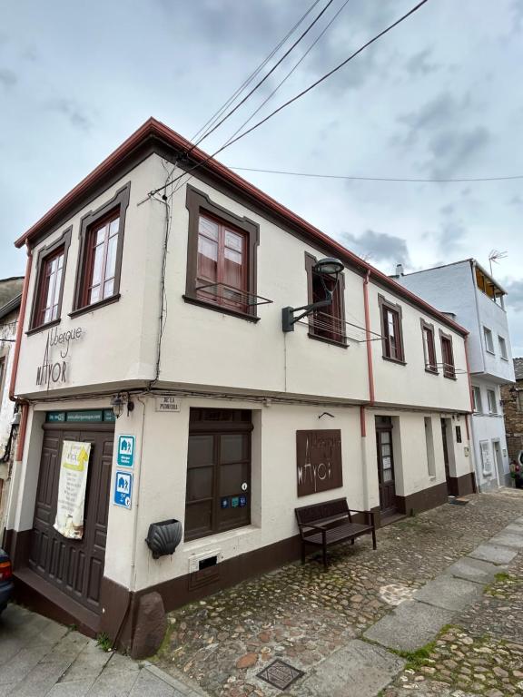 un edificio blanco con un banco delante en Albergue Mayor, en Sarria