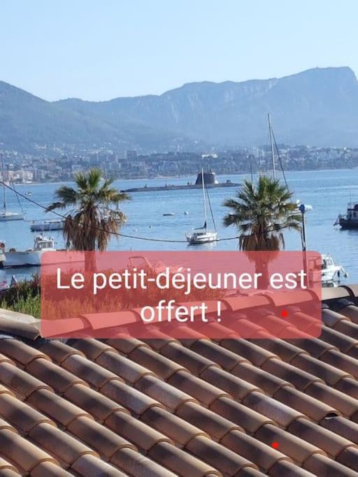 un panneau sur le toit d'un bâtiment avec des palmiers dans l'établissement Studio plage, parking gratuit et terrasse privée., à Saint-Mandrier-sur-Mer