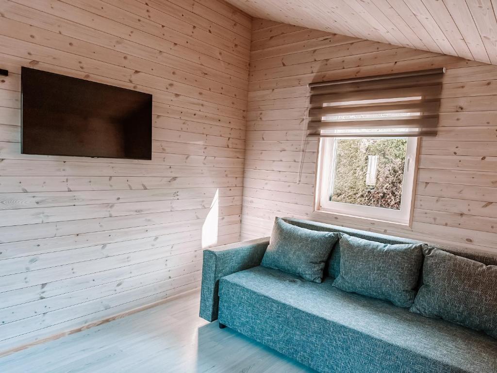 uma sala de estar com um sofá e uma televisão em Ramybės kampelis em Šventoji