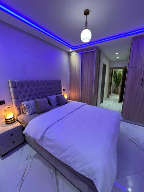 una camera da letto con un grande letto con illuminazione viola di Appartement Wow ad Al-Ḥoseyma